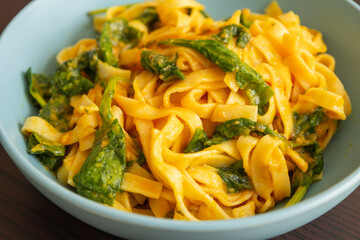 delicious pumpkin tagliatelle pasta with spinach fall cozy dinner served in blue bowl close up