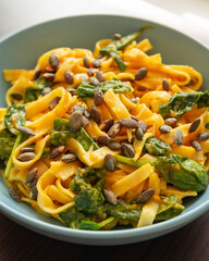 delicious pumpkin tagliatelle pasta with spinach fall cozy dinner served in blue bowl close up