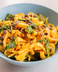 delicious pumpkin tagliatelle pasta with spinach fall cozy dinner served in blue bowl close up