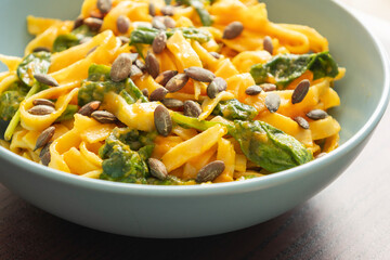 delicious pumpkin tagliatelle pasta with spinach fall cozy dinner served in blue bowl close up