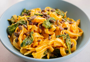 delicious pumpkin tagliatelle pasta with spinach fall cozy dinner served in blue bowl close up