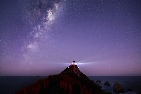 The Milky Way rising over Nugget Point Lighthouse. Southland. New Zealand.