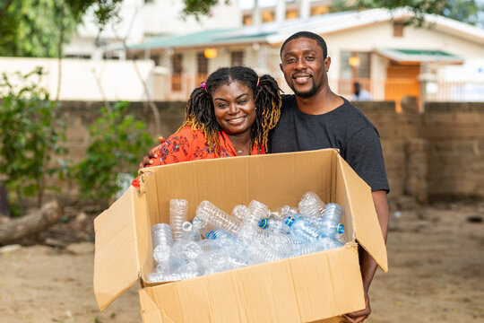 Happy African couple recycling plastic bottles outdoors. Sustainability concept.