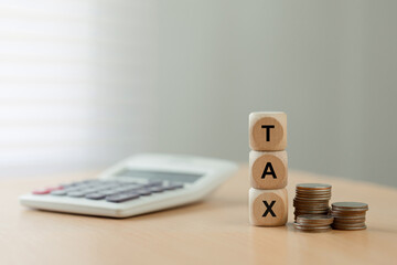 Tax planning concept with wooden blocks spelling TAX beside stacks of coins and a blurred calculator on a desk. perfect for filing season tips, budgeting, business finance, savings, and deadlines.