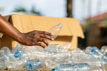 African man recycling plastic bottles, environmental awareness, sustainability.