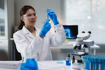 Fototapeta premium Young woman scientist examining test tube in laboratory