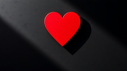 Red heart-shaped object on a dark textured surface, conveying emotion through minimalist design.