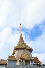 Fototapeta premium Golden stupa of Wat Traimit in Bangkok’s Chinatown, rising against a bright blue sky. A famous Thai temple known for the Golden Buddha and stunning architecture.