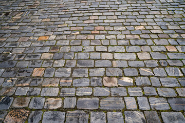 Close up of old cobblestone pavement street in Bergen with green grass sprouting between stones