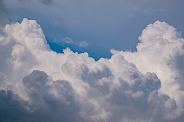Fluffy white clouds swirl gently against a bright blue background, creating a serene atmosphere