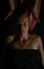 Close-up of female client receiving therapeutic shoulder massage. Moody lighting, warm tones, and soothing hands convey wellness and relaxation