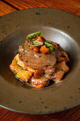 Tender beef on a plate with savory sauce and crispy vegetables surrounds it