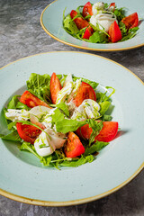 Tasty salad with fresh arugula, ripe tomatoes, and creamy mozzarella with dressing