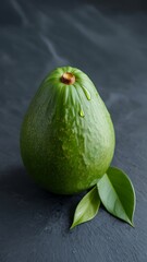 Single fresh green avocado with leaves on a textured surface isolated