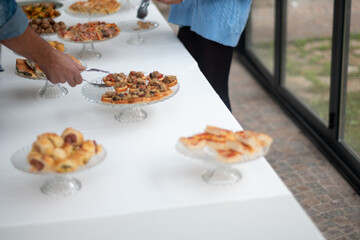 A long white table displays an assortment of small appetizers and finger foods ready for guests to enjoy at a casual gathering or event