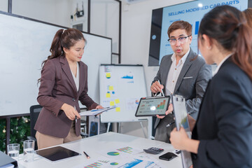Asian businessman standing and presenting her work on a laptop
