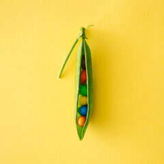 Creative food concept made with peas and colorful candies on a yellow backround.Flat lay