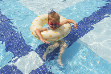 Little girl floating in swimming pool with swimming ring 