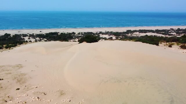 aerial footage captures the vast, wind swept Patara Sand Dunes meeting the serene turquoise waters of the Mediterranean Sea in Antalya, Turkey. This stunning natural landscape, known for its golden sa