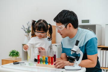 toddler girl scientist study using pipette dropping liquid with test tube and beaker. learning science with father