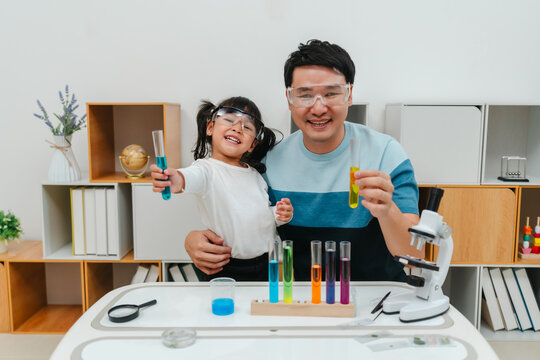 father and toddler girl scientist learning science with test tube and beaker