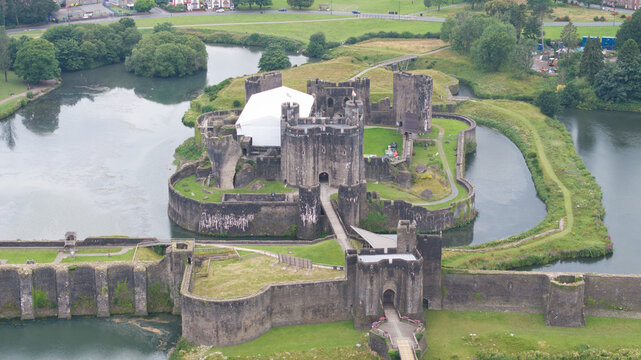 Aerial view of the imposing Caerphilly Castle rising from the water, its stone walls and towers reflecting in the moat, a testament to history, Caerphilly, Wales, United Kingdom.