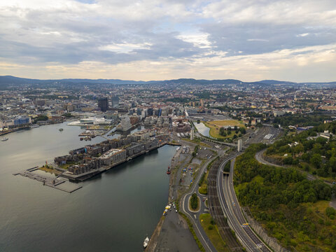 Aerial view of the Astrup Fearnley Museum and Aker Brygge contrasting with the city's skyline under a cloudy sky, Oslo, Oslo, Norway.