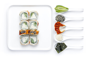 Sushi roll on a white plate on a perfectly white background with ingredients for it in white spoons isolated
