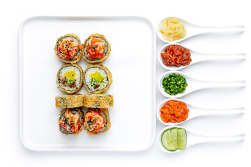 Sushi roll on a white plate on a perfectly white background with ingredients for it in white spoons isolated