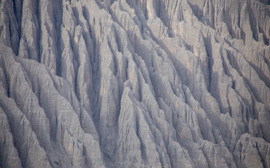 Fototapeta premium Dushanzi, Xinjiang landscape of eroded cliffs and deep ridges in a dry canyon with unique geological formations under a clear blue sky. 