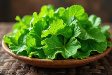 A vibrant bowl of fresh, leafy greens, showcasing their rich, verdant color and delicate texture, rests on a rustic woven surface.