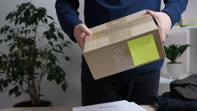 Across a counter, a customers hands slide a box marked with a Return sticker towards a specialist, who accepts it, counts out a sum of cash, and hands the refund back to the client. 