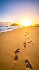 Footprints lead to sunrise on beach
