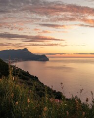 Fototapeta premium Serene Coastal Sunset Over Calm Waters with Lush Greenery