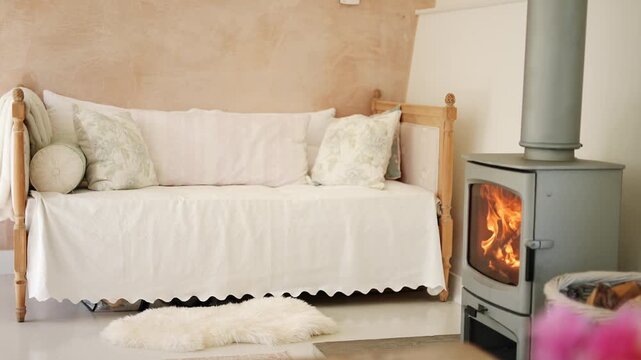 A white couch with pillows and a blanket on it. A fireplace is in the background. The couch is in a living room