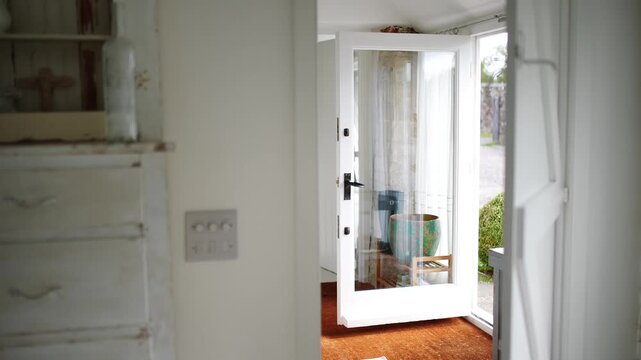 A white door with a glass window is open in a room. The room is empty and has a simple, clean design