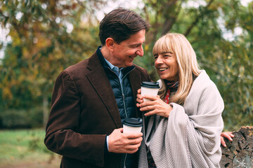 Senior couple enjoying autumn park with coffee