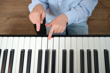 Kid with tiny hands playing piano. Little boy learning to play musical instrument. Early childhood education and music development for young children. A child aged 4 years (four years old)