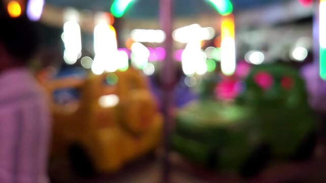 Colorful blurred night shot of a big lighted Ferris wheel in an Indian funfair park, with an abstract blurred background of people gathering and shopping at the local city night market.