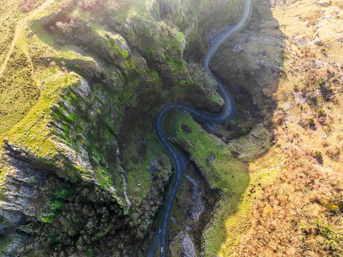 Aerial view of a winding road snaking through the rugged, verdant cliffs of Cheddar Gorge, a testament to nature's grandeur, Cheddar, England, United Kingdom.