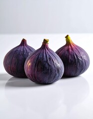 Three purple figs on a white surface