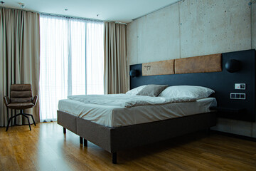 Modern minimalist bedroom interior with white bed blue accent wall and soft daylight

