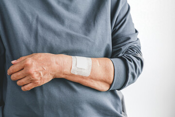 Close up of elderly person hand with adhesive medical bandage on wrist after injury or surgery, concept of healthcare, treatment and recovery