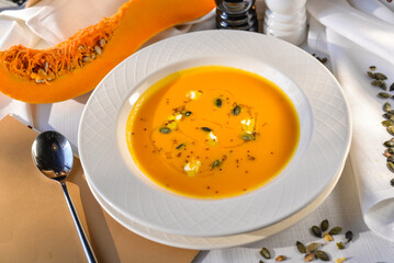 pumpkin cream soup in a white plate on a table with food decor