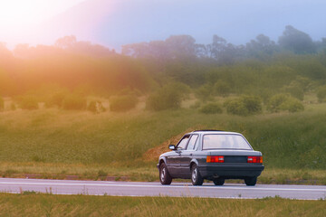 Fototapeta premium Vintage 90s vehicle driving on country road