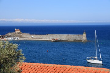 View of sailboat in bay with Saint-Vincent chapel visible in Mediterranean seaside town of Collioure, Pyr&eacute;n&eacute;es-Orientales, France
