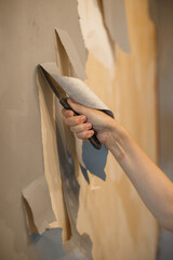 Hand scraping old wallpaper during renovation project