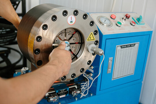 Worker crimping hydraulic hose using machinery