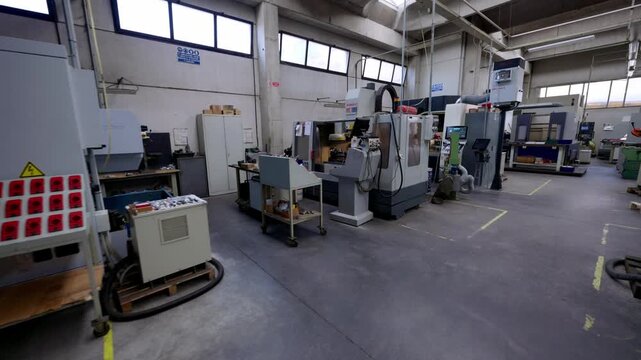 Wide shot of a clean, modern machine shop or manufacturing factory floor with several CNC machines, highlighting high-tech automation and precision engineering