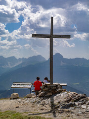 Large Wooden Cross at the Summit of Plan de Corones and a Seated Couple admiring the landscape below, Italy